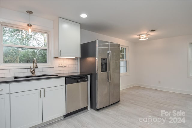 kitchen with white cabinetry, sink, hanging light fixtures, light hardwood / wood-style flooring, and appliances with stainless steel finishes