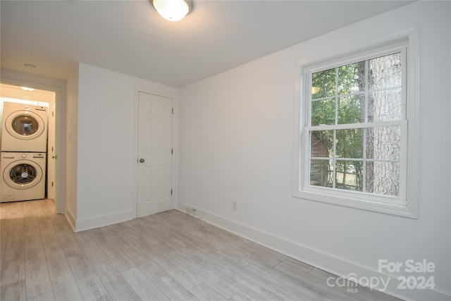 laundry room with stacked washer / dryer and light hardwood / wood-style floors