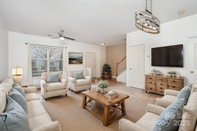 living room featuring ceiling fan with notable chandelier and light wood-type flooring