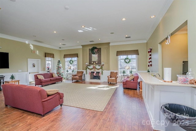 living room with light wood-type flooring, ornamental molding, and a wealth of natural light