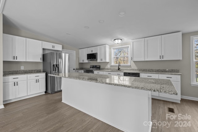 kitchen with white cabinets, appliances with stainless steel finishes, light wood-type flooring, and a kitchen island