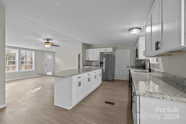 kitchen with white cabinetry, stainless steel fridge with ice dispenser, sink, and light stone countertops