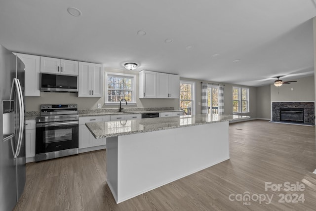 kitchen featuring a kitchen island, white cabinets, a healthy amount of sunlight, and appliances with stainless steel finishes