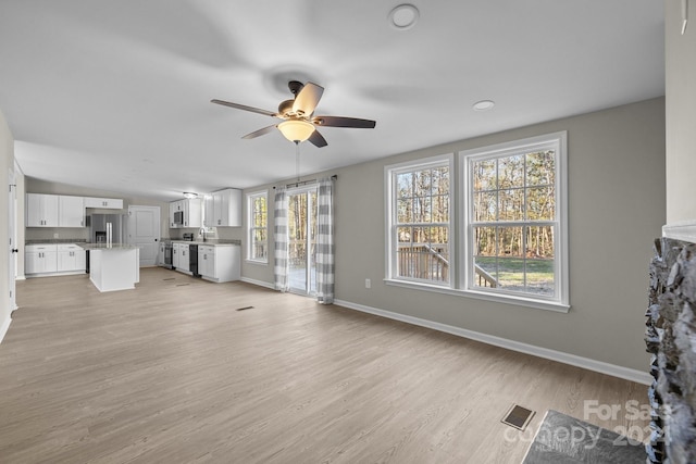 unfurnished living room featuring ceiling fan and light hardwood / wood-style floors