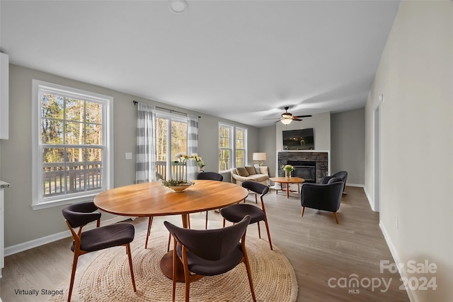 dining area featuring hardwood / wood-style flooring, a stone fireplace, and a healthy amount of sunlight