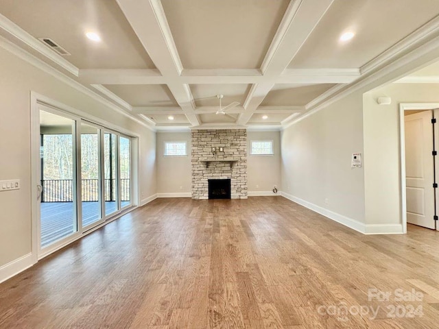 unfurnished living room featuring hardwood / wood-style floors, a stone fireplace, ornamental molding, and beamed ceiling