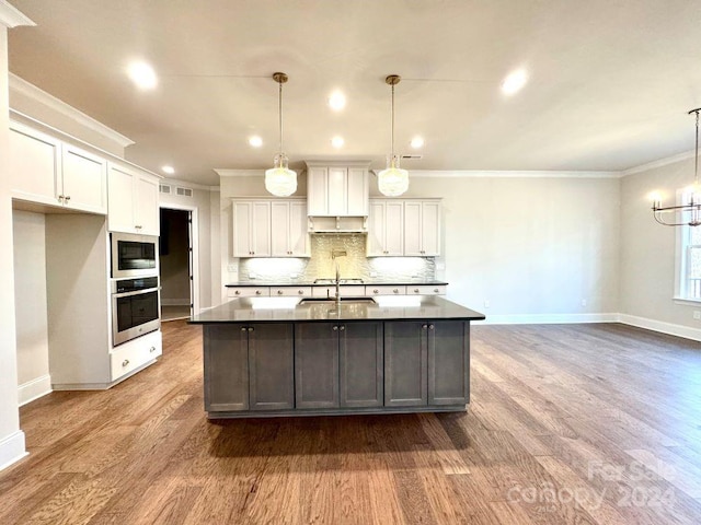 kitchen with appliances with stainless steel finishes, pendant lighting, and wood-type flooring