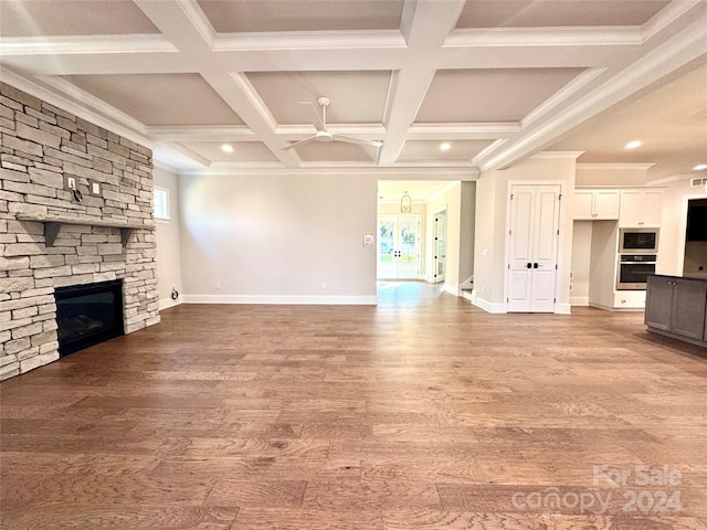 unfurnished living room with beam ceiling, ceiling fan, a fireplace, and hardwood / wood-style flooring