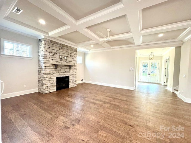 unfurnished living room featuring a stone fireplace, crown molding, hardwood / wood-style floors, and coffered ceiling