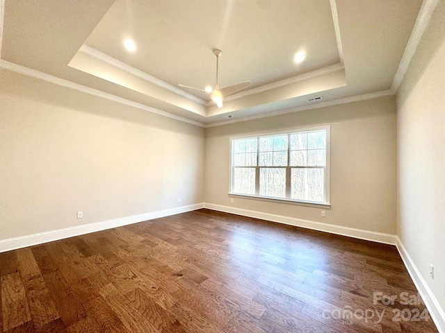 empty room featuring ornamental molding, a raised ceiling, ceiling fan, and dark wood-type flooring