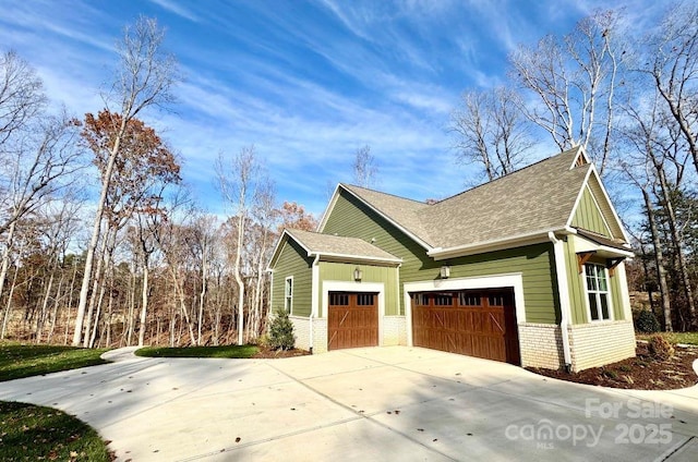 view of home's exterior featuring a garage, driveway, roof with shingles, and brick siding