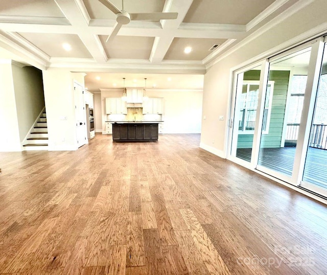 unfurnished living room featuring ceiling fan, light wood finished floors, stairway, and coffered ceiling