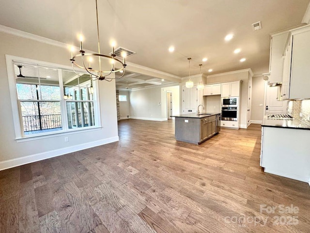 kitchen with dark countertops, open floor plan, an inviting chandelier, stainless steel appliances, and crown molding