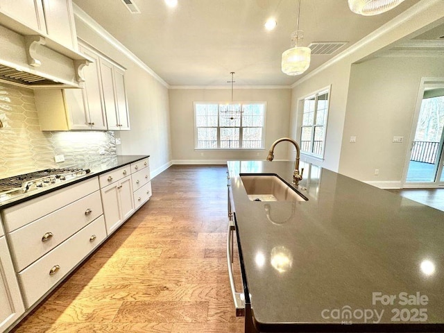 kitchen with crown molding, a healthy amount of sunlight, a sink, and backsplash