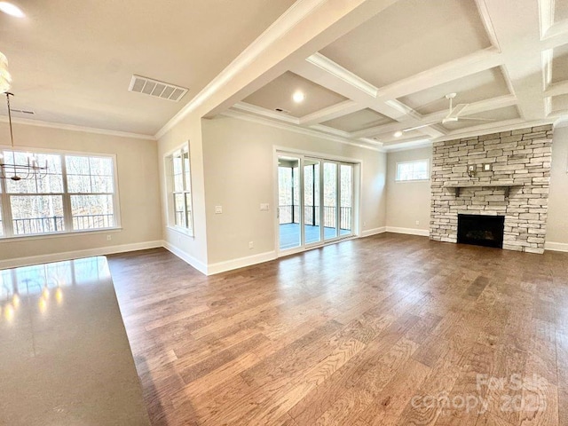 unfurnished living room with a fireplace, coffered ceiling, wood finished floors, visible vents, and crown molding