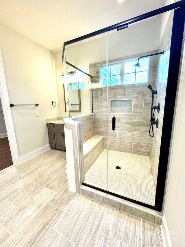 bathroom with baseboards, vanity, and a shower stall