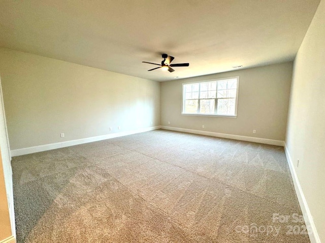 carpeted empty room with ceiling fan, visible vents, and baseboards