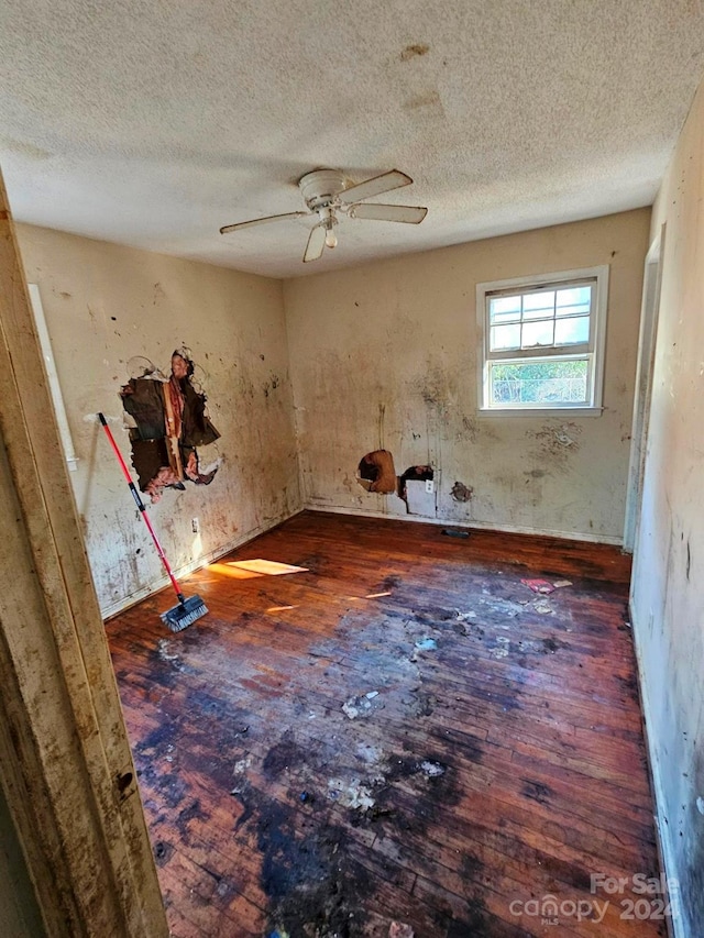 misc room with ceiling fan, dark hardwood / wood-style flooring, and a textured ceiling