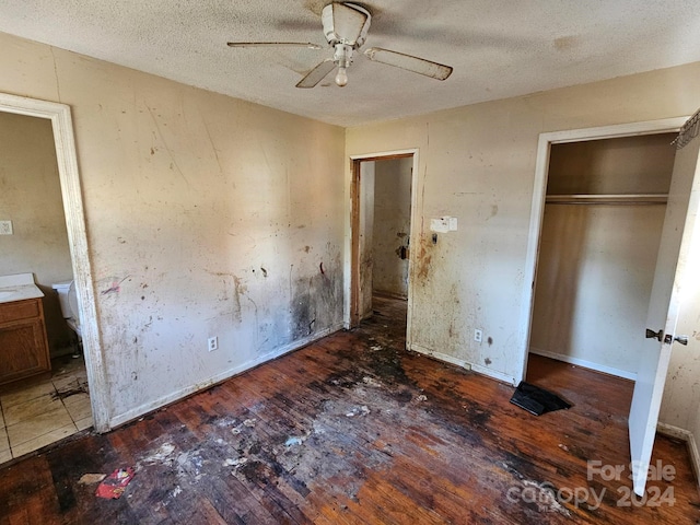 unfurnished bedroom featuring a textured ceiling, ceiling fan, and dark wood-type flooring