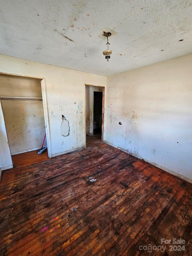 unfurnished bedroom with a textured ceiling and dark wood-type flooring