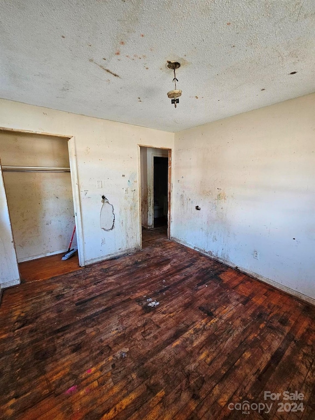 unfurnished bedroom with a textured ceiling and dark wood-type flooring