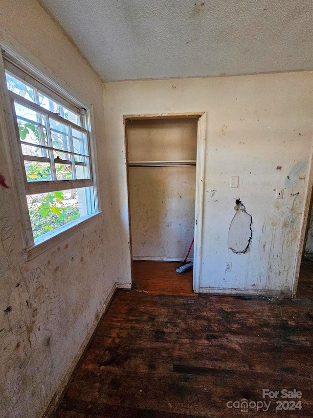 interior space with a textured ceiling, a closet, and dark wood-type flooring