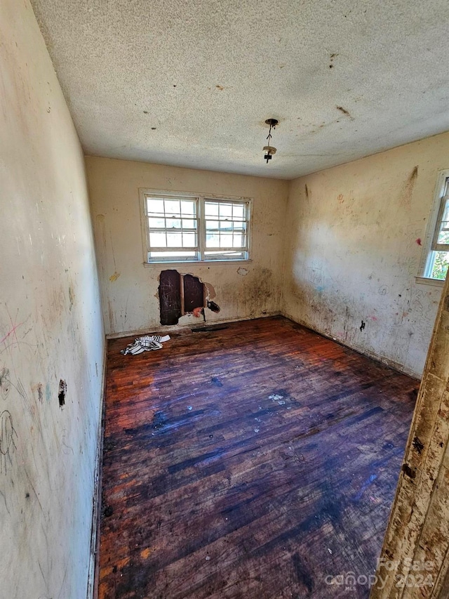 empty room featuring a textured ceiling and dark hardwood / wood-style floors