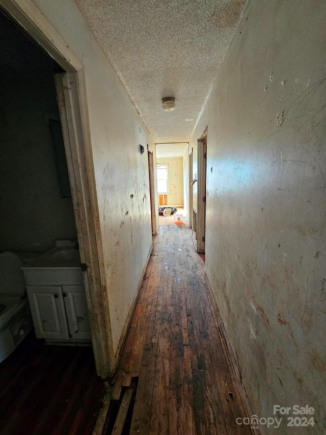 corridor featuring a textured ceiling and dark hardwood / wood-style floors