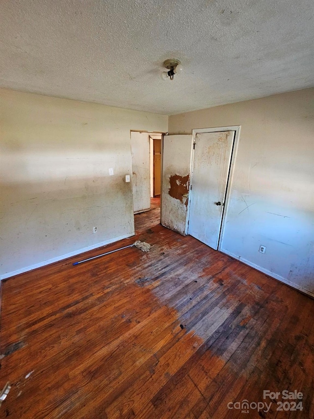 unfurnished bedroom with a textured ceiling and dark hardwood / wood-style flooring