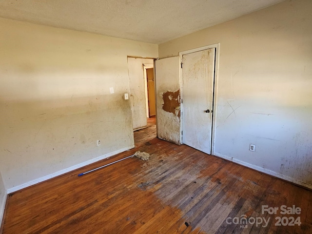 unfurnished bedroom with dark wood-type flooring and a textured ceiling