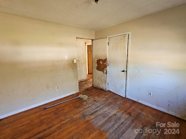 unfurnished bedroom with a textured ceiling and dark hardwood / wood-style floors