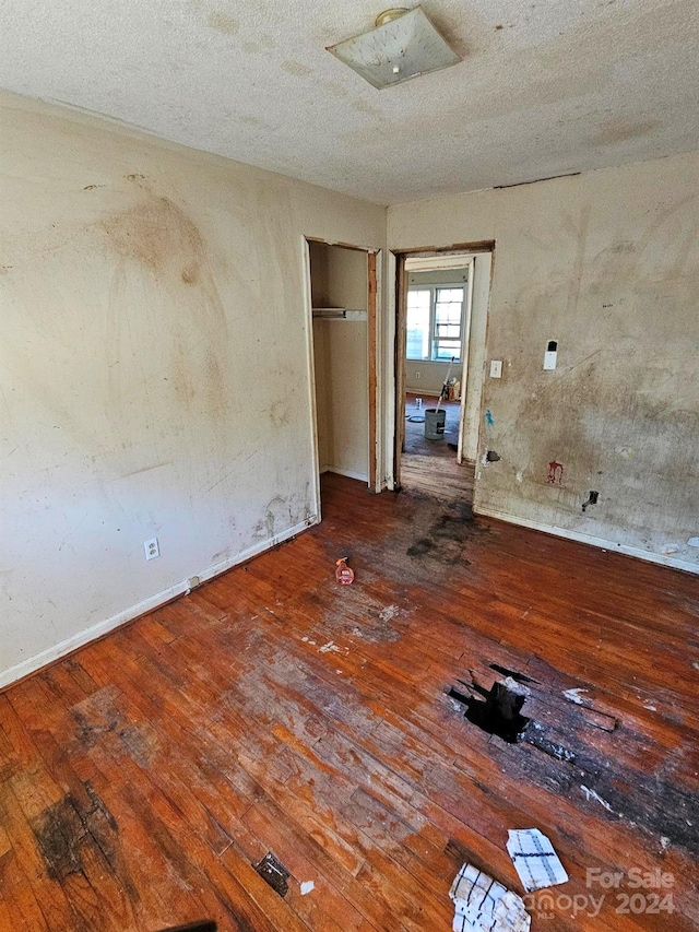 unfurnished room featuring wood-type flooring and a textured ceiling