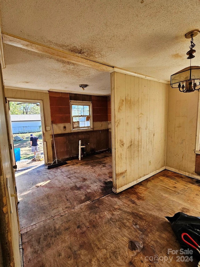 interior space featuring wooden walls, dark hardwood / wood-style floors, a textured ceiling, and a notable chandelier