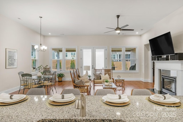 living room with a tile fireplace, french doors, ceiling fan with notable chandelier, and wood-type flooring