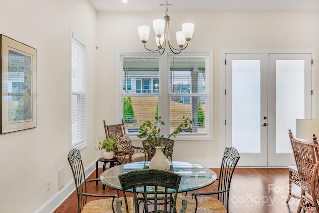 dining room with french doors, wood-type flooring, and an inviting chandelier