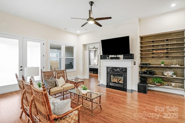 living room featuring ceiling fan, hardwood / wood-style floors, a high end fireplace, and french doors