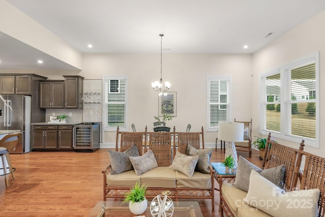 living room featuring beverage cooler, a chandelier, and light hardwood / wood-style floors