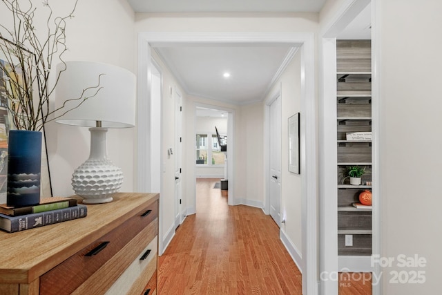 hall with light hardwood / wood-style floors and ornamental molding