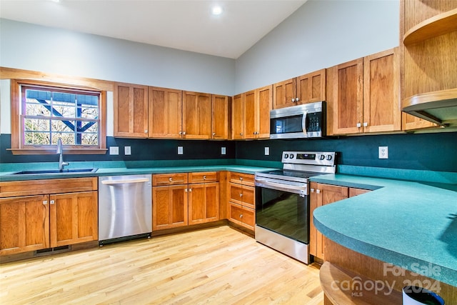 kitchen featuring appliances with stainless steel finishes, high vaulted ceiling, light hardwood / wood-style flooring, and sink