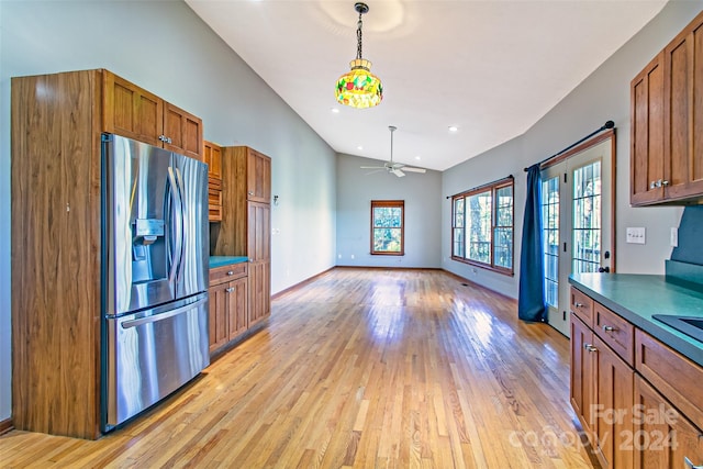 kitchen featuring ceiling fan, sink, hanging light fixtures, stainless steel fridge with ice dispenser, and light wood-type flooring