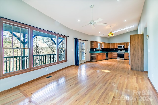 kitchen with appliances with stainless steel finishes, light hardwood / wood-style floors, vaulted ceiling, and ceiling fan