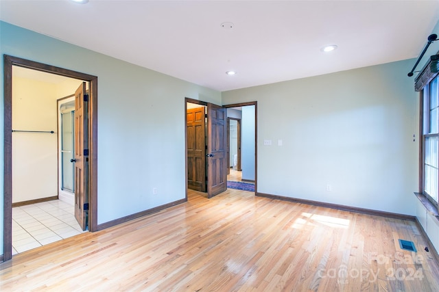 unfurnished bedroom featuring multiple windows, a closet, and light hardwood / wood-style floors