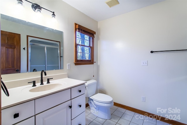 bathroom with tile patterned flooring, vanity, toilet, and a shower with door