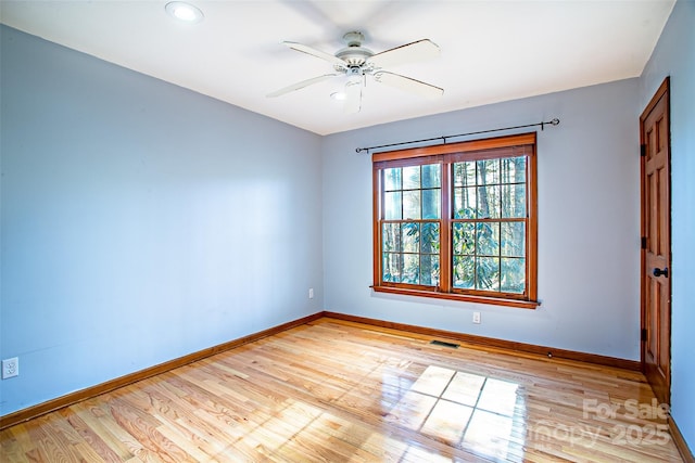 spare room featuring light wood finished floors, visible vents, and baseboards