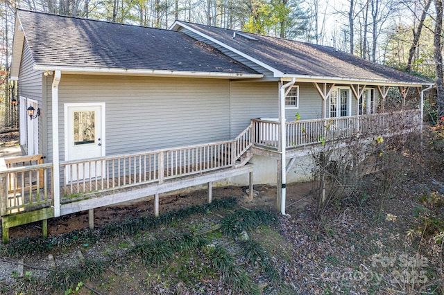 exterior space with a deck and roof with shingles