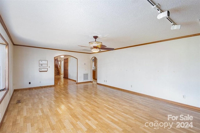 spare room with rail lighting, crown molding, ceiling fan, light wood-type flooring, and a textured ceiling