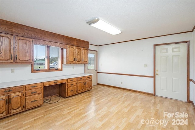 kitchen with built in desk, ornamental molding, and light wood-type flooring