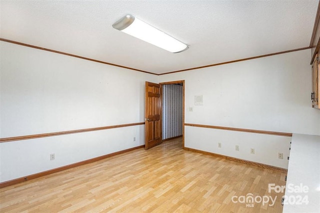 unfurnished room with crown molding, light wood-type flooring, and a textured ceiling