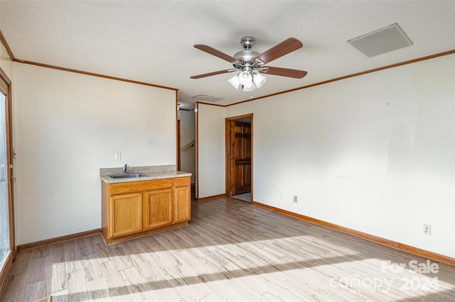 interior space with ceiling fan, sink, light hardwood / wood-style flooring, a textured ceiling, and ornamental molding