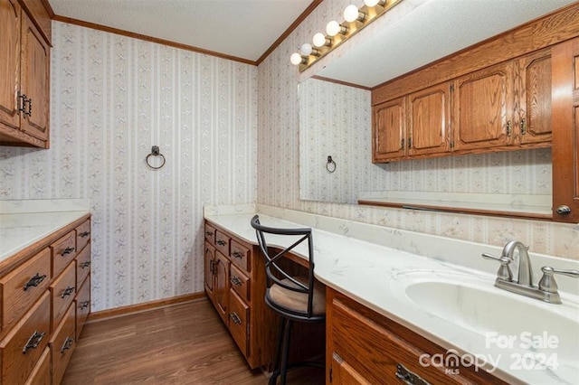 bathroom with crown molding, hardwood / wood-style floors, vanity, and a textured ceiling